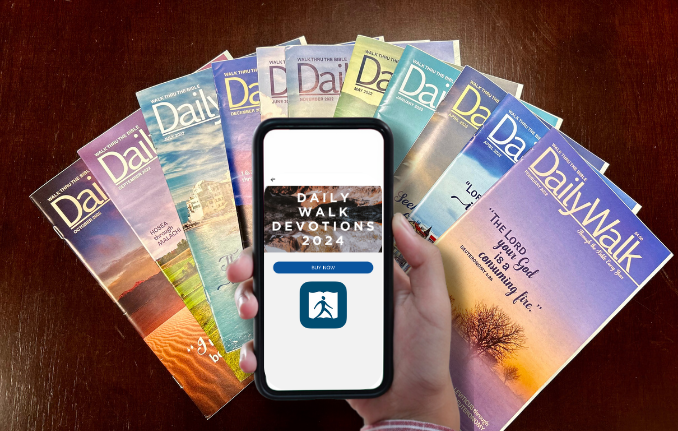 An photo of an array with DailyWalk Magazines covers with a hand holding a phone with "Daily Walk Devotions 2024" on it