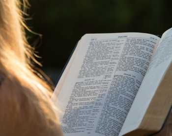 blonde hair on the corner of the screen with an open bible in her hands